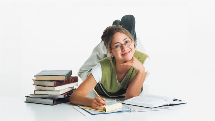 Young Smiling Woman Studying with Books Surrounding Her